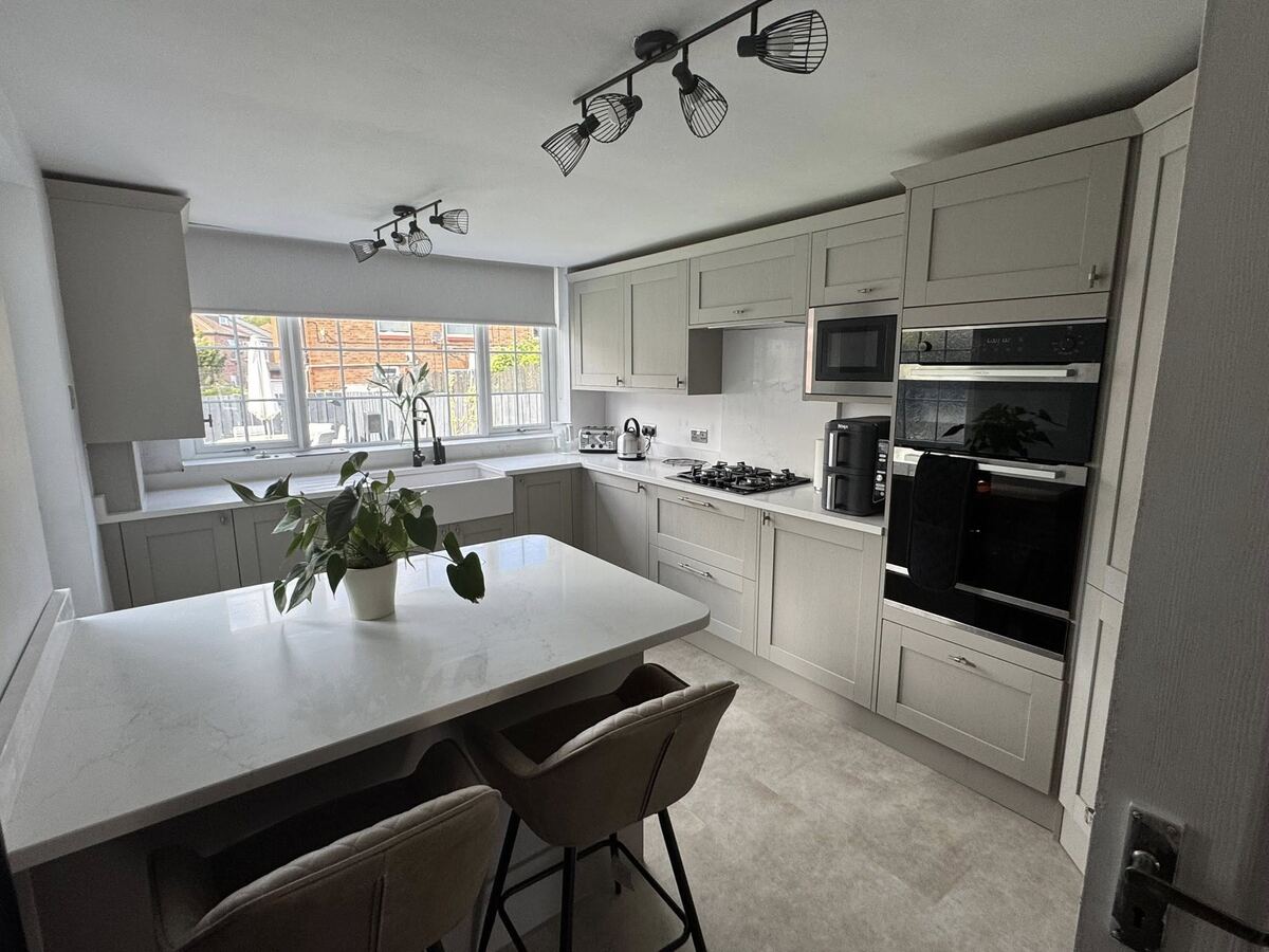 Light grey shaker kitchen with a white-topped peninsula and bar stools